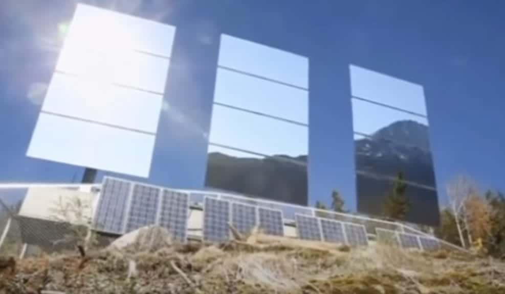 Three panel mirrors sitting on the side of. a mountain reflecting sunlight.